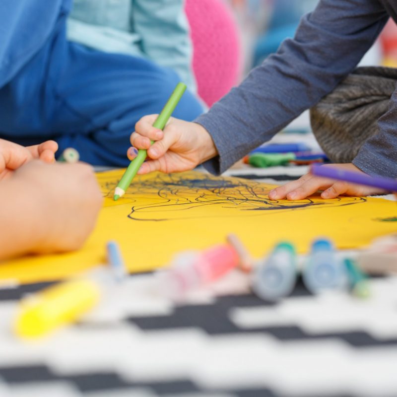 Close-up of kindergarten children painting with friends during classes